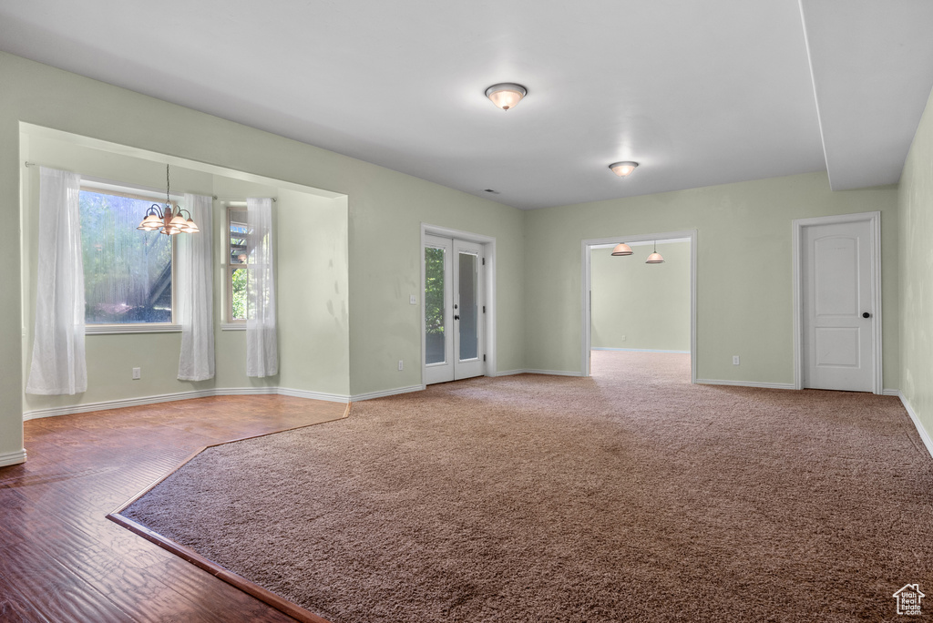 Empty room featuring a chandelier and baseboards
