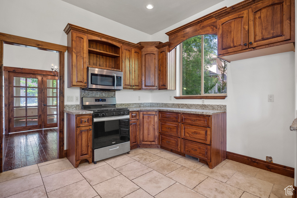 Kitchen with appliances with stainless steel finishes, healthy amount of natural light, brown cabinets, open shelves, and recessed lighting