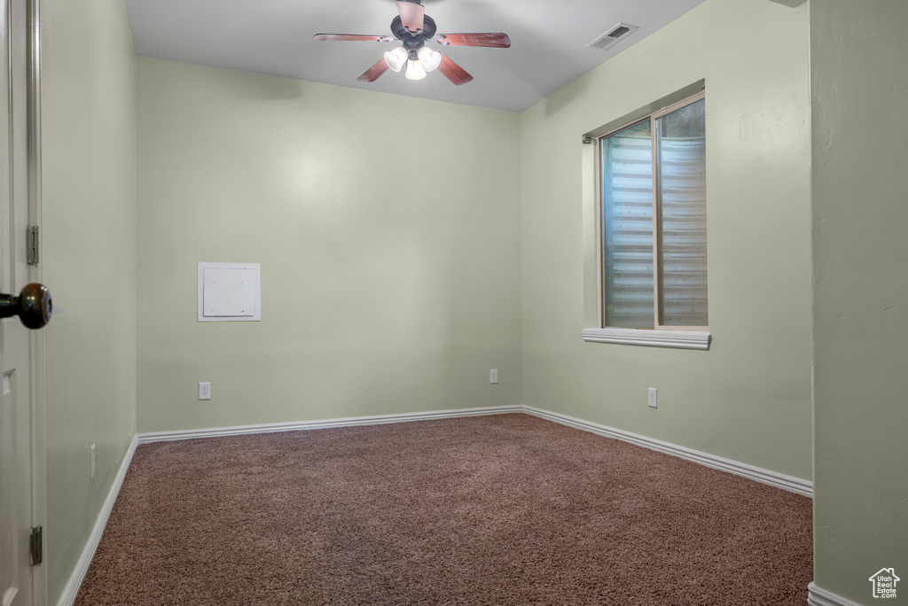 Carpeted spare room with a ceiling fan and baseboards