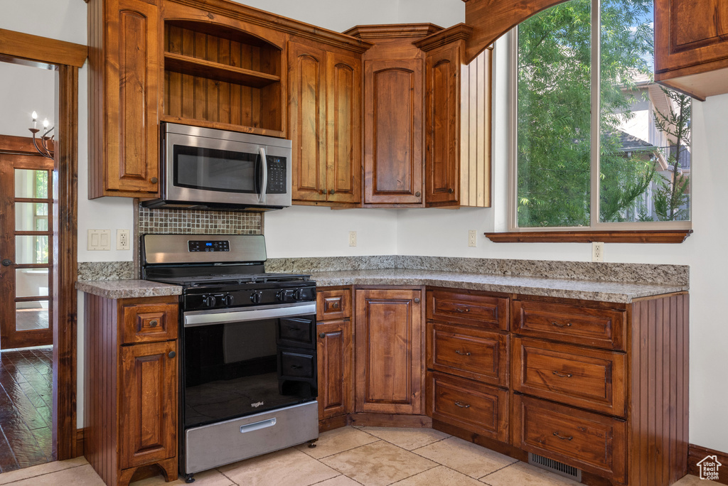 Kitchen featuring appliances with stainless steel finishes, brown cabinets, and open shelves