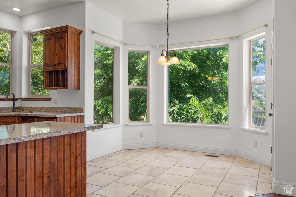 Unfurnished dining area with light tile patterned flooring and a chandelier