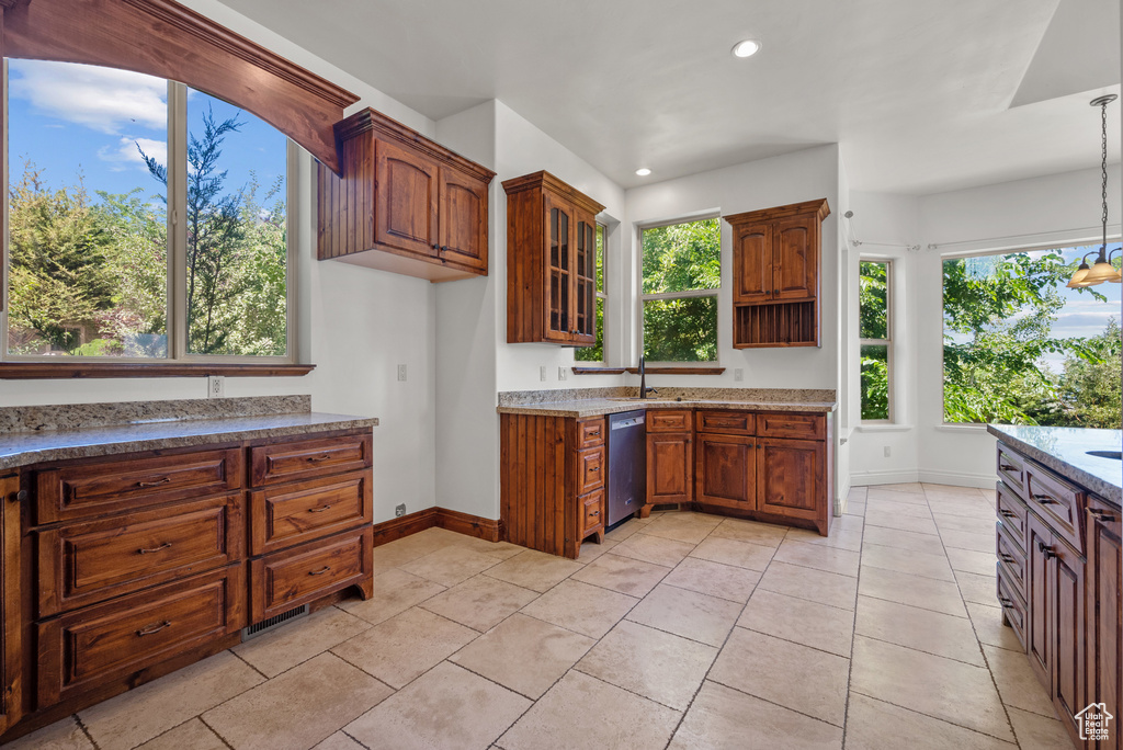 Kitchen with dishwasher, recessed lighting, brown cabinetry, light stone counters, and glass insert cabinets