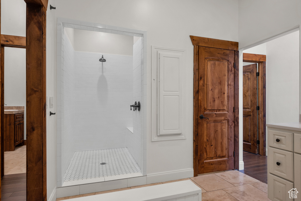Bathroom with tiled shower, vanity, and tile patterned floors