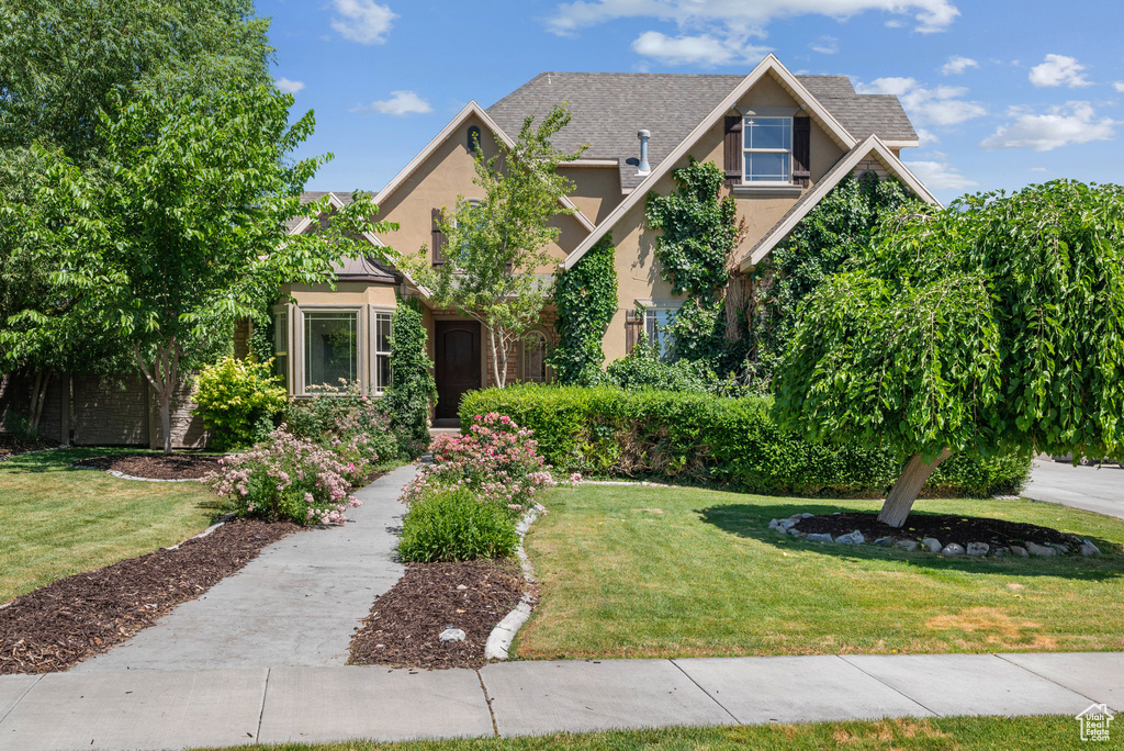 View of front facade featuring stucco siding and a front yard