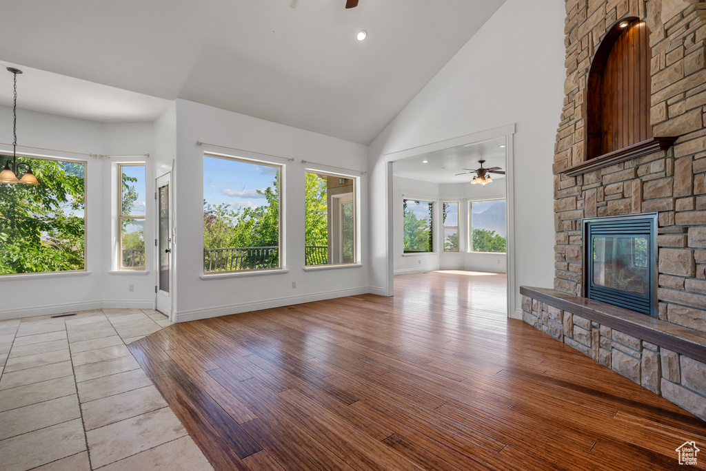 Unfurnished living room with a ceiling fan, a fireplace, healthy amount of natural light, high vaulted ceiling, and recessed lighting