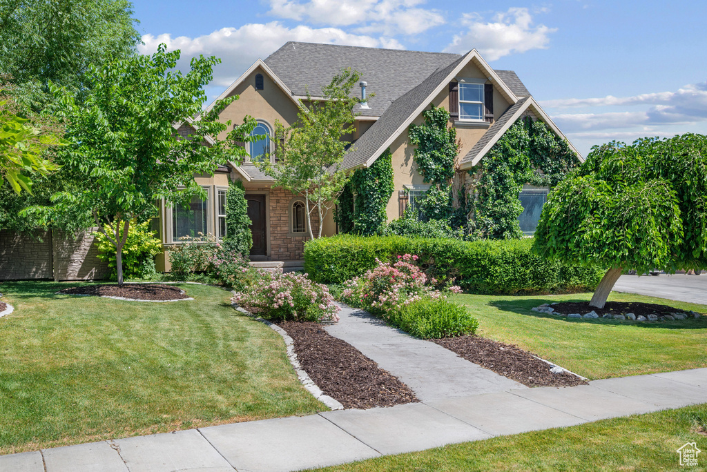 Craftsman inspired home with stucco siding, a front yard, stone siding, and a shingled roof