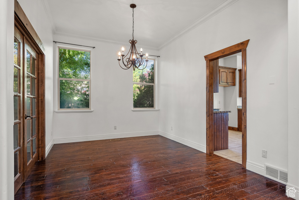 Empty room with hardwood / wood-style flooring, a chandelier, and ornamental molding