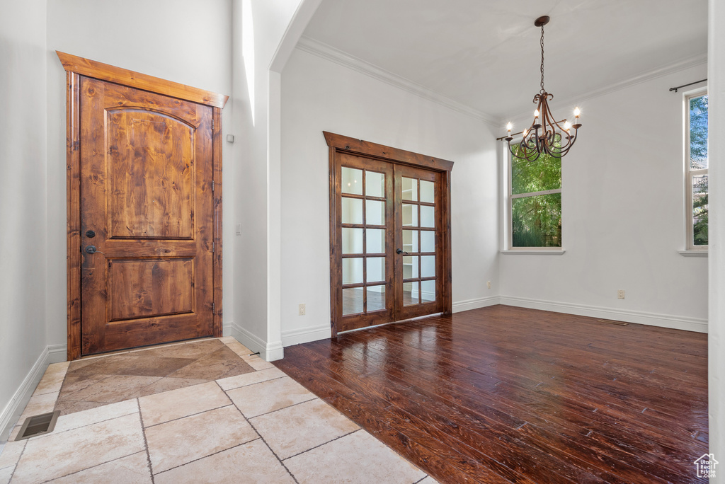 Foyer featuring ornamental molding, french doors, a chandelier, and arched walkways