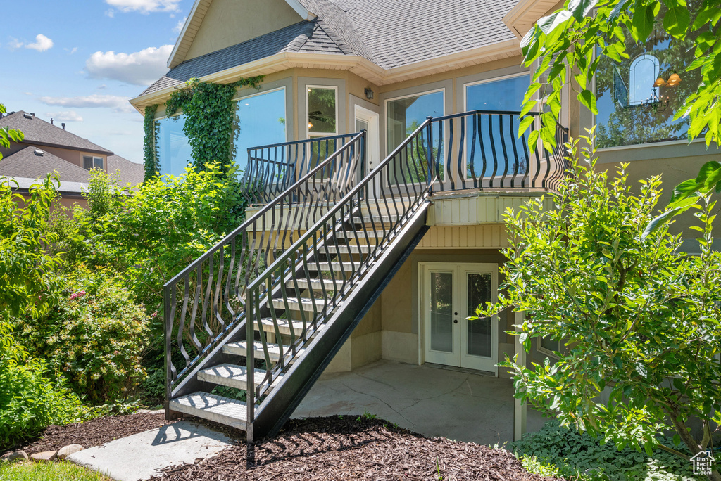 View of exterior entry featuring roof with shingles, french doors, a patio, and stucco siding