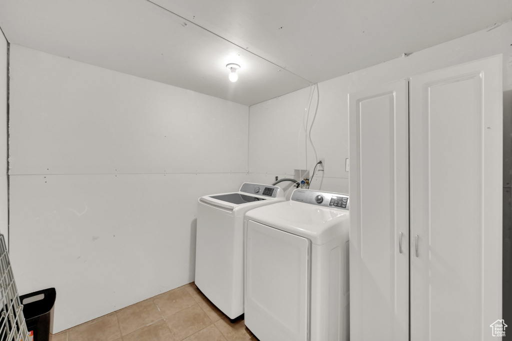 Laundry area with washer and clothes dryer and light tile patterned floors