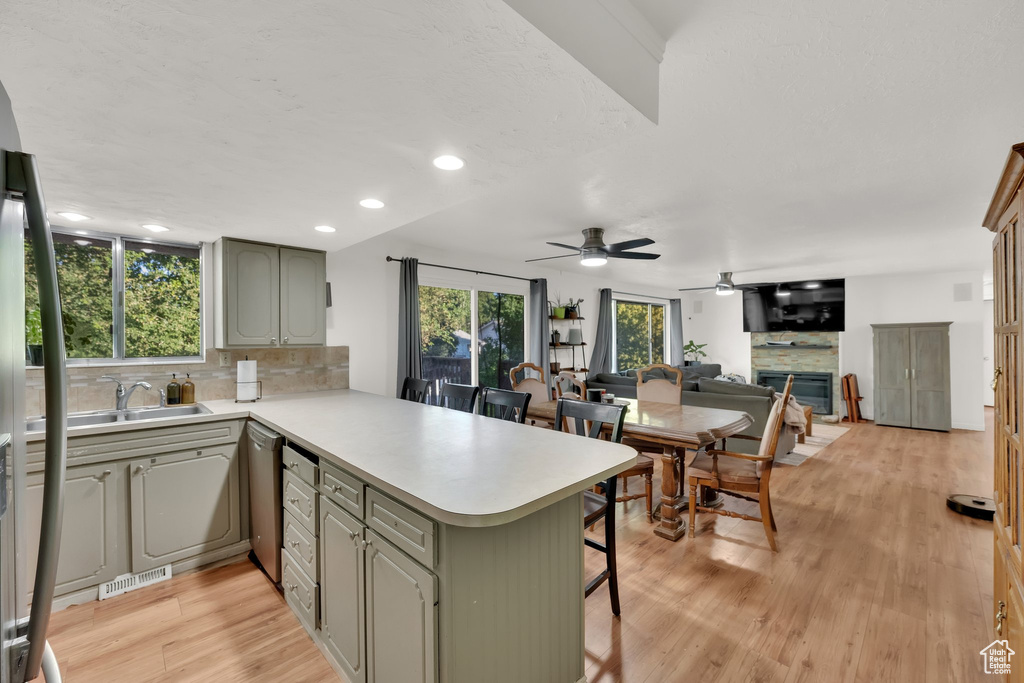 Kitchen with a peninsula, light countertops, a kitchen breakfast bar, ceiling fan, and decorative backsplash