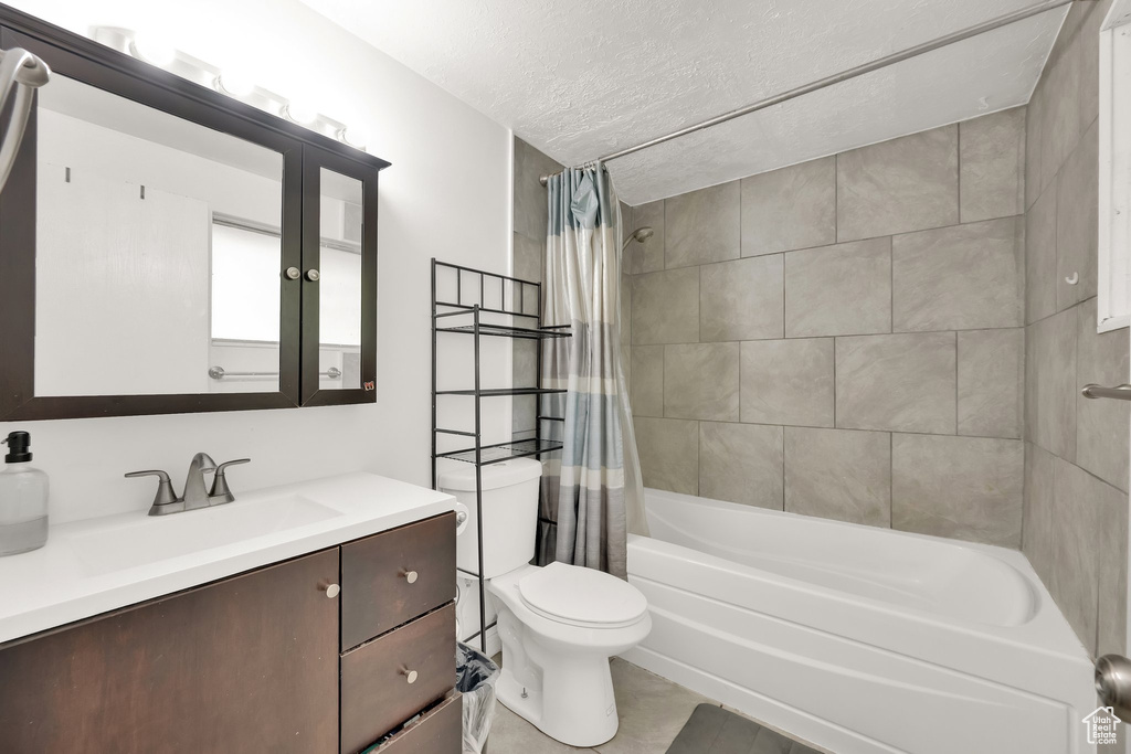 Full bathroom with vanity, shower / bath combination with curtain, tile patterned flooring, and a textured ceiling