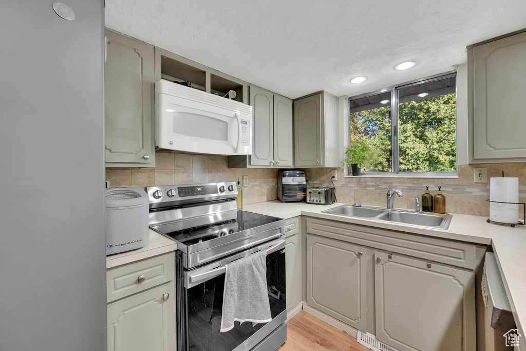 Kitchen featuring appliances with stainless steel finishes, light countertops, tasteful backsplash, light wood-style floors, and recessed lighting