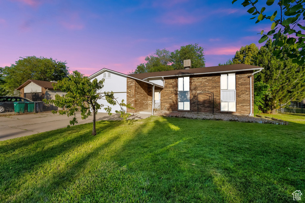 View of front of house featuring driveway, a front yard, brick siding, and a garage