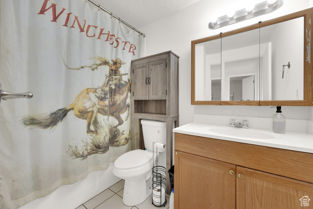 Full bath with tile patterned floors, vanity, a shower with shower curtain, and a textured ceiling