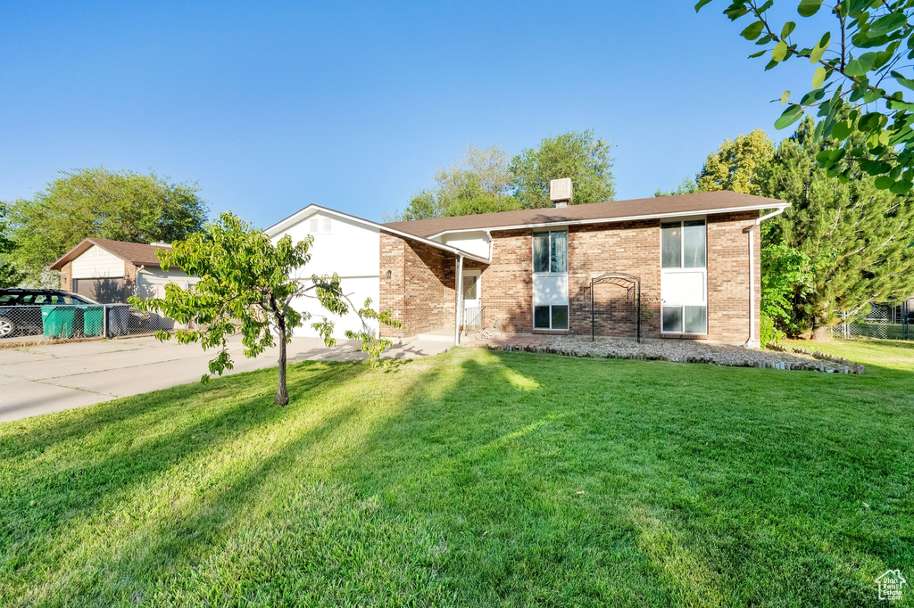 View of front facade with driveway, a front yard, and brick siding