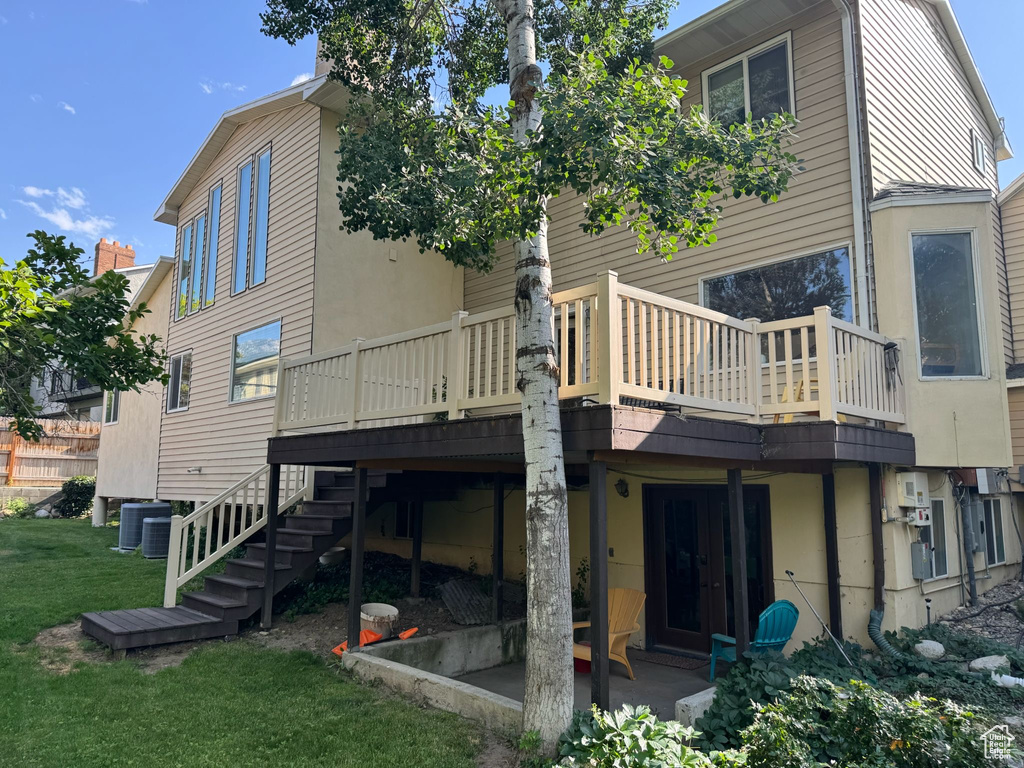 Rear view of house featuring a yard, a wooden deck, and stairs
