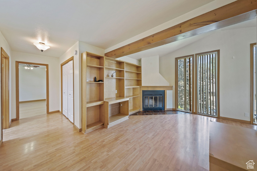 Unfurnished living room featuring a fireplace with flush hearth, light wood-style floors, and a ceiling fan