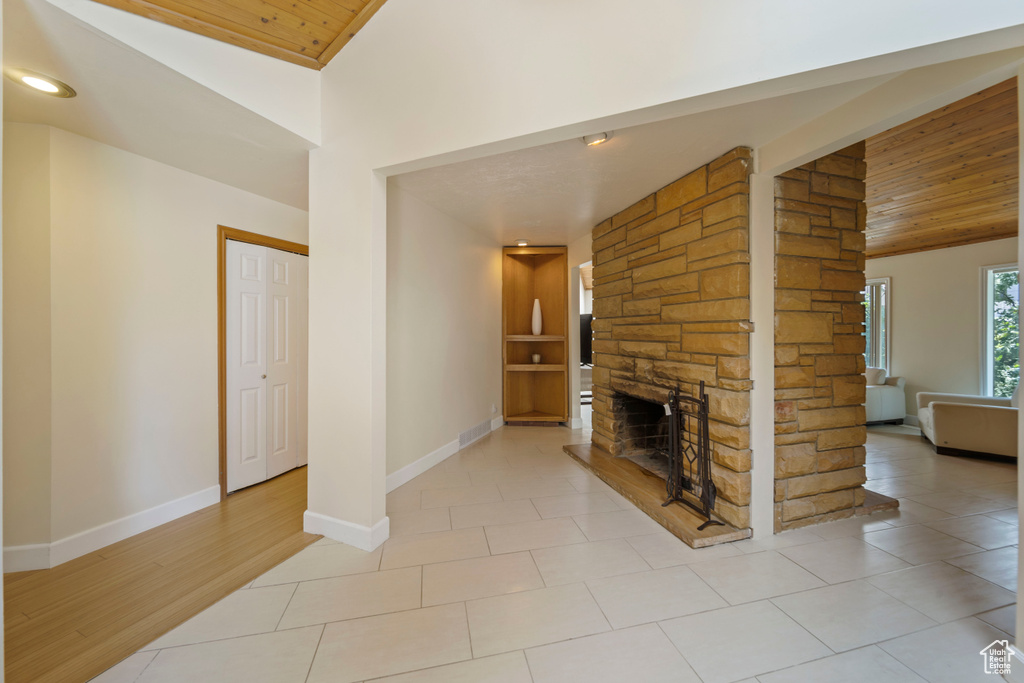 Unfurnished living room featuring wooden ceiling, a fireplace, light tile patterned floors, and high vaulted ceiling