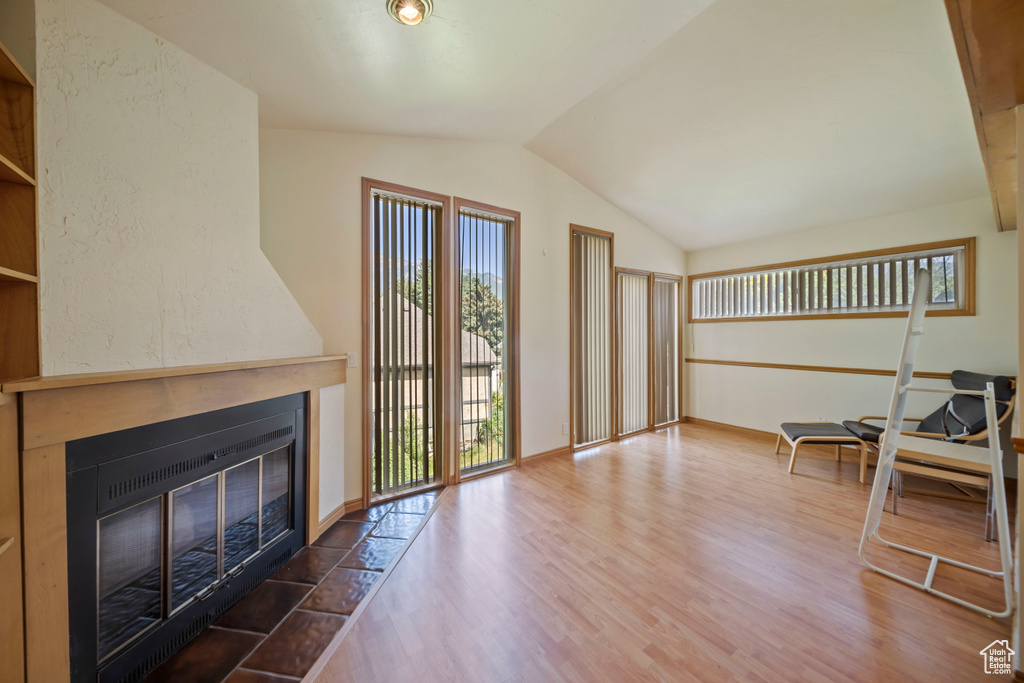 Living room with lofted ceiling, a fireplace with flush hearth, and wood finished floors