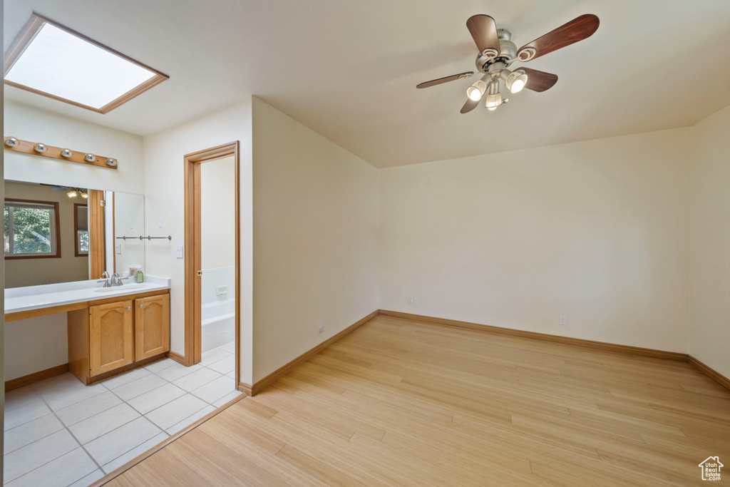 Bonus room featuring light wood-type flooring, a ceiling fan, and a skylight