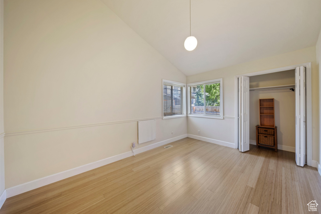 Unfurnished bedroom with light wood-style flooring, a closet, and vaulted ceiling