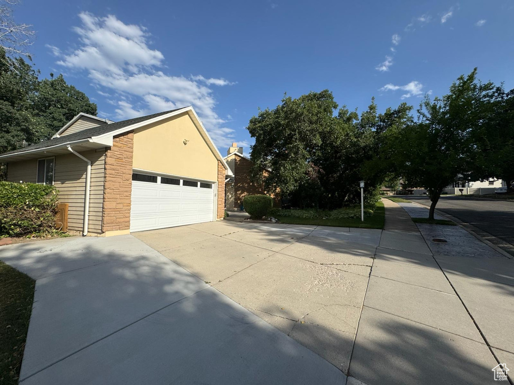 View of side of property with stone siding, concrete driveway, and a garage