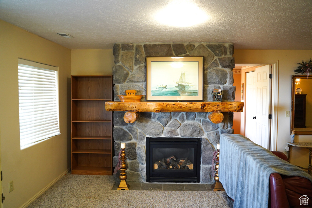 Living area featuring a fireplace, a textured ceiling, and carpet flooring