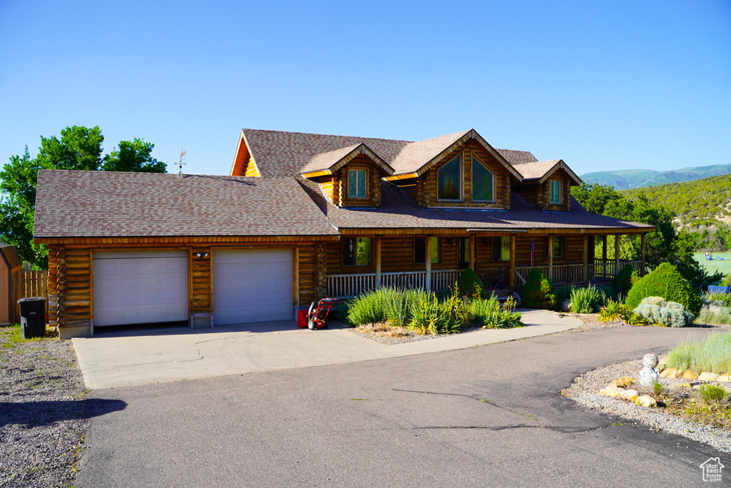 Log home with log exterior, a garage, covered porch, and concrete driveway