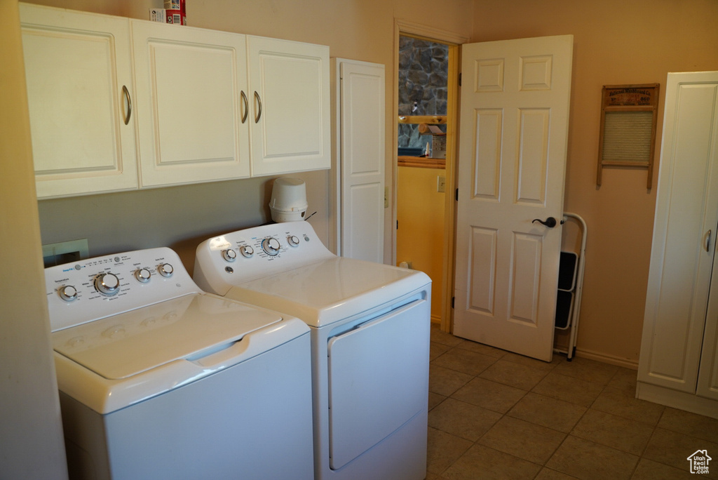 Washroom with independent washer and dryer, cabinet space, and tile patterned flooring