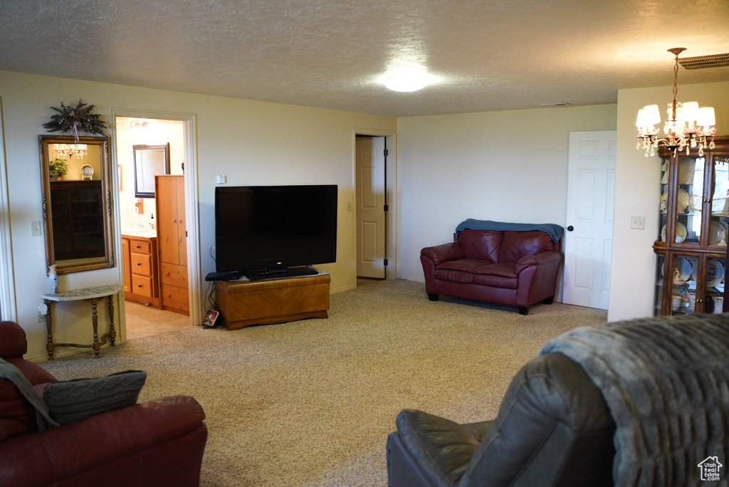 Living room with a chandelier, light carpet, and a textured ceiling