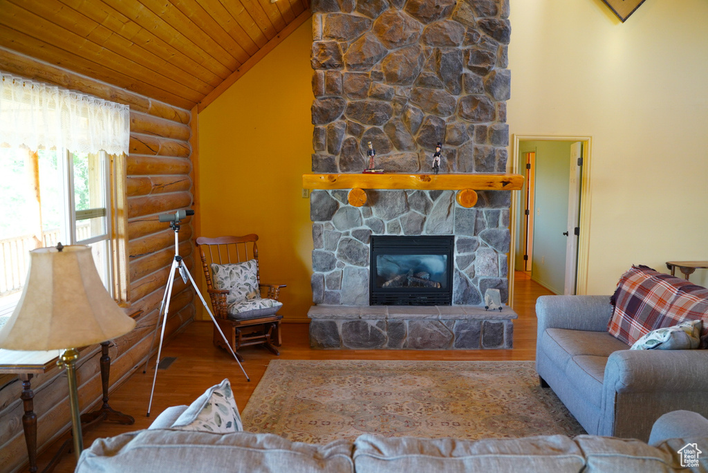 Living area featuring rustic walls, wooden ceiling, wood finished floors, a fireplace, and vaulted ceiling