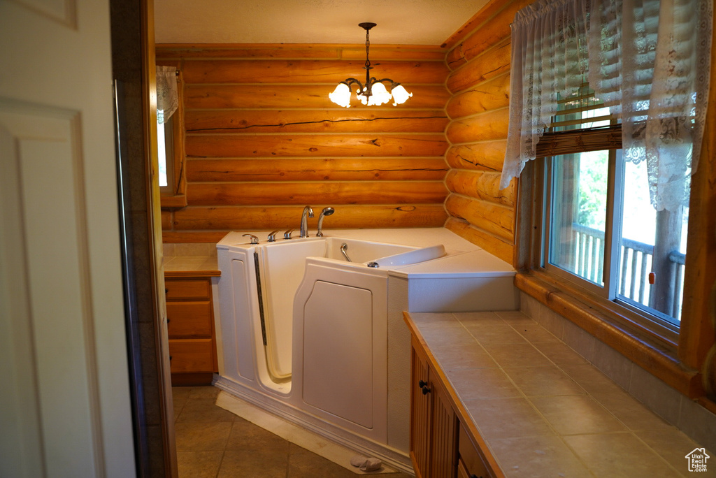 Washroom featuring rustic walls, independent washer and dryer, a chandelier, and light tile patterned floors