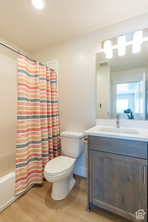 Bathroom with vanity, wood finished floors, and shower / bath combo with shower curtain