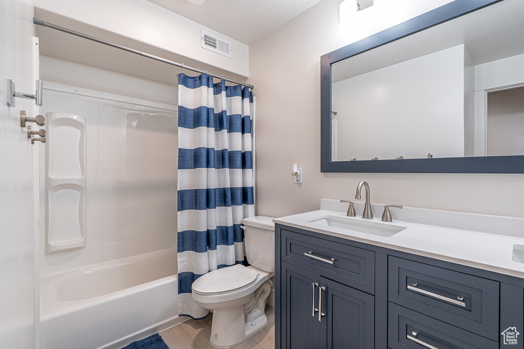 Bathroom with vanity, shower / bathtub combination with curtain, and wood finished floors
