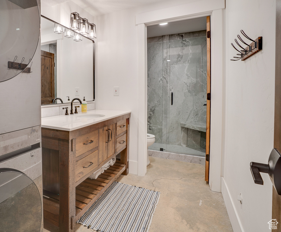 Bathroom with vanity, a marble finish shower, and concrete flooring