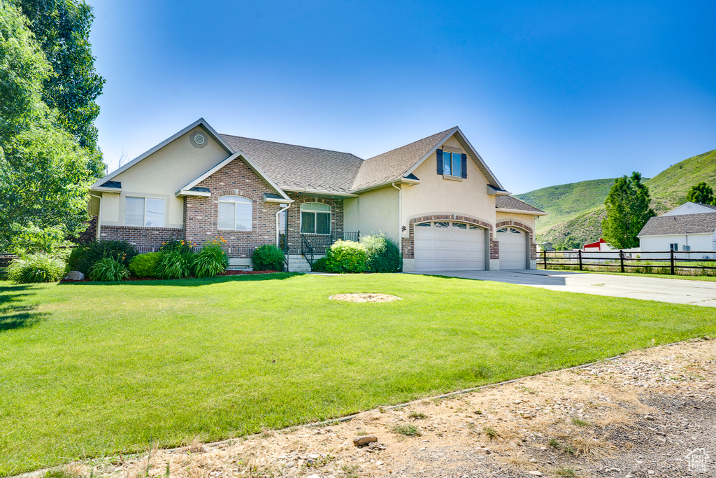 View of front of home featuring driveway, brick siding, a mountain view, a garage, and stucco siding