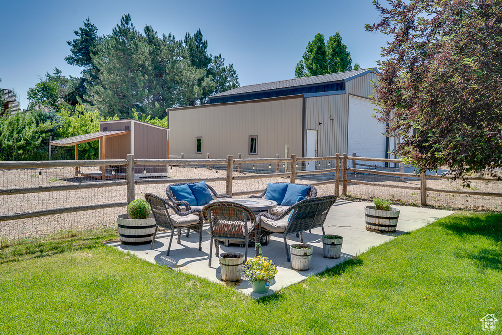 View of patio / terrace featuring a pole building, an outbuilding, a detached garage, and an outdoor hangout area