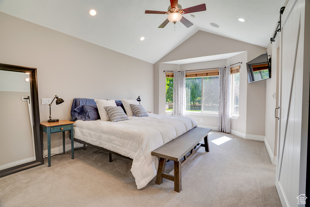 Bedroom with lofted ceiling, light colored carpet, recessed lighting, a barn door, and a ceiling fan