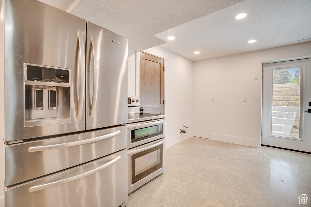 Kitchen featuring appliances with stainless steel finishes, recessed lighting, concrete floors, and a textured ceiling