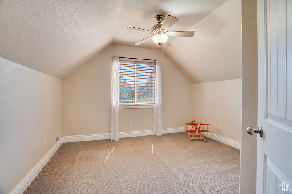 Bonus room featuring carpet flooring, lofted ceiling, ceiling fan, and a textured ceiling
