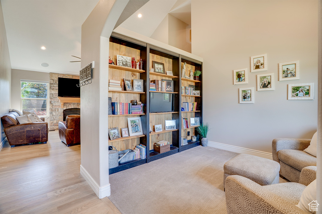 Living area with a stone fireplace, recessed lighting, and light wood-style flooring