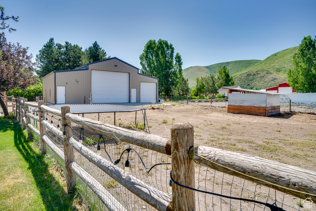 View of yard featuring a detached garage, an outbuilding, and a mountain view