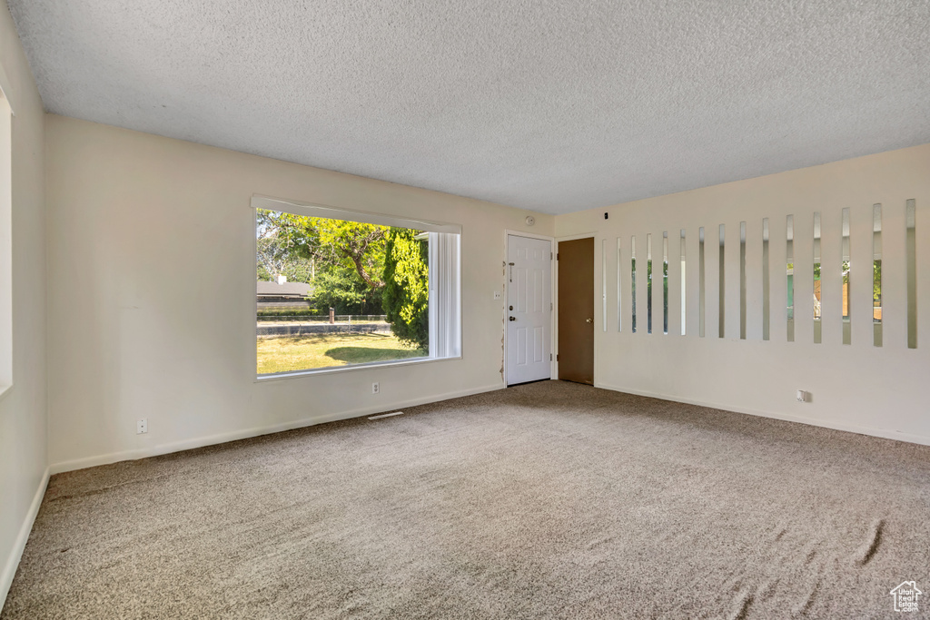 Empty room featuring a textured ceiling and carpet