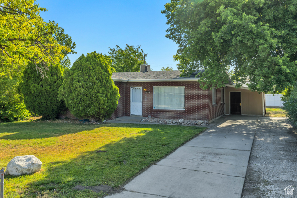 View of front of house featuring a front lawn, concrete driveway, brick siding, a carport, and roof with shingles