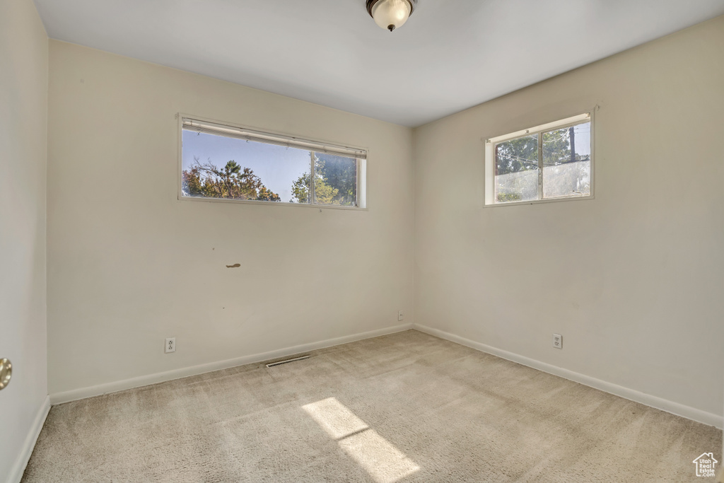 Empty room with healthy amount of natural light and carpet floors