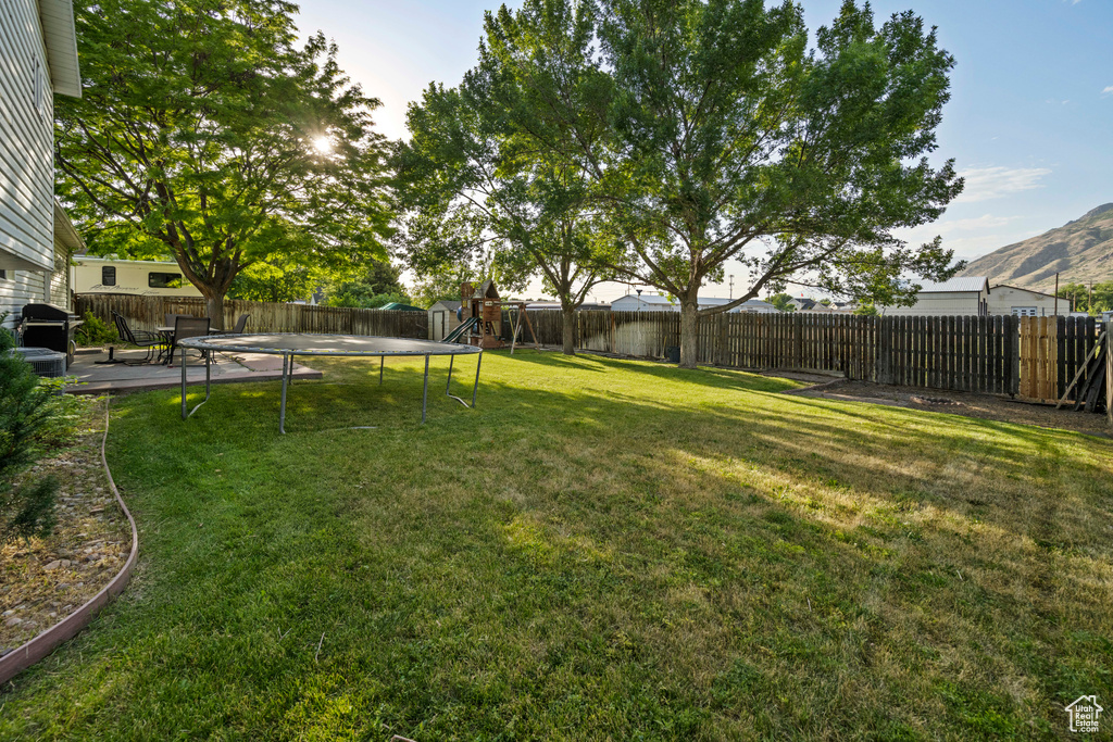 Fenced backyard featuring a trampoline