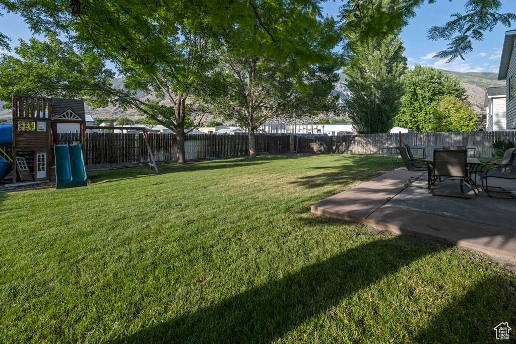 Fenced backyard with a patio and a playground