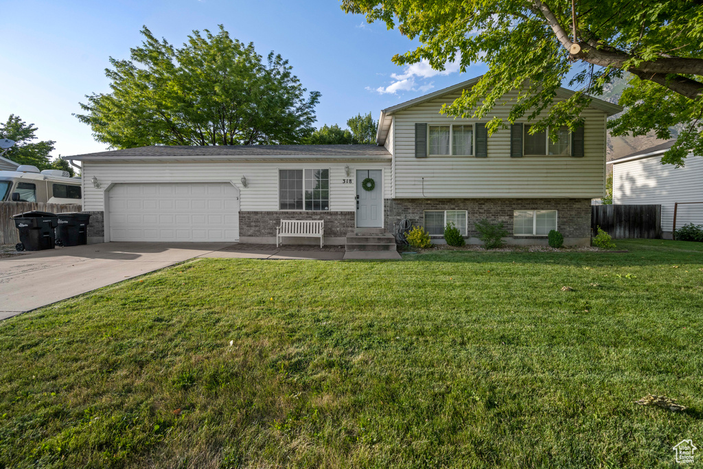 Tri-level home featuring an attached garage, concrete driveway, and brick siding