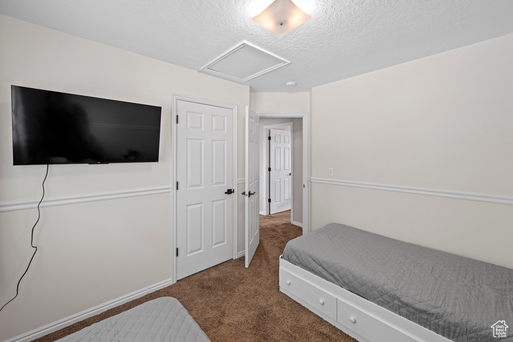 Bedroom featuring attic access, carpet, and a textured ceiling